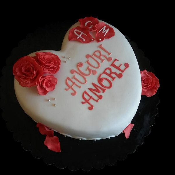 Torta a forma di cuore decorata con rose rosse in pasta di zucchero per un compleanno